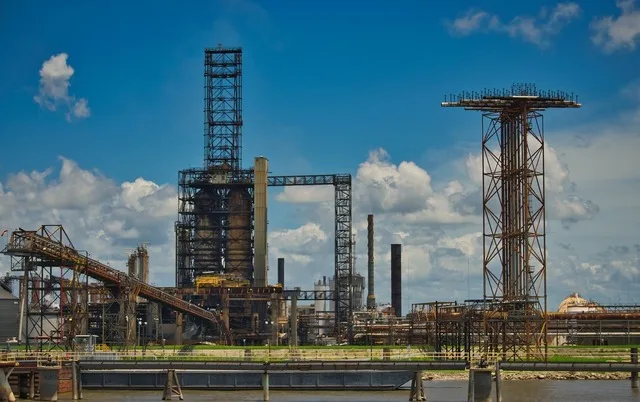 Rafinărie industrială cu structuri metalice și cer senin.