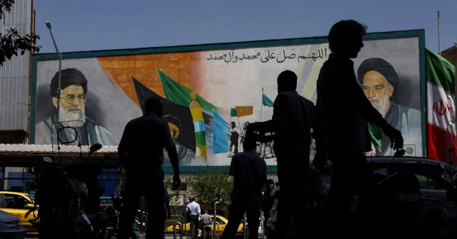 Oameni care trec pe lângă un mural în Teheran, Iran.