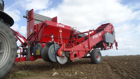 Un utilaj agricol pe câmp, pregătit pentru recoltarea cartofilor.