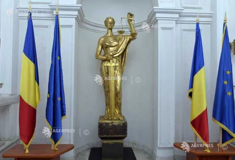 Statuia Justiției în fața drapelului României și Uniunii Europene.