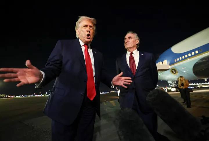 Donald Trump vorbește cu gesturi expresive lângă un oficial.