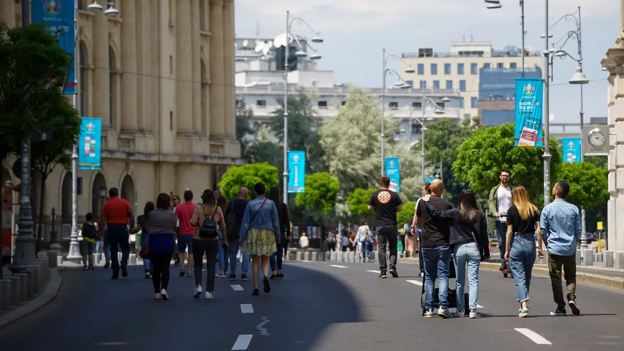 Oameni plimbându-se pe o stradă aglomerată dintr-un oraș european.