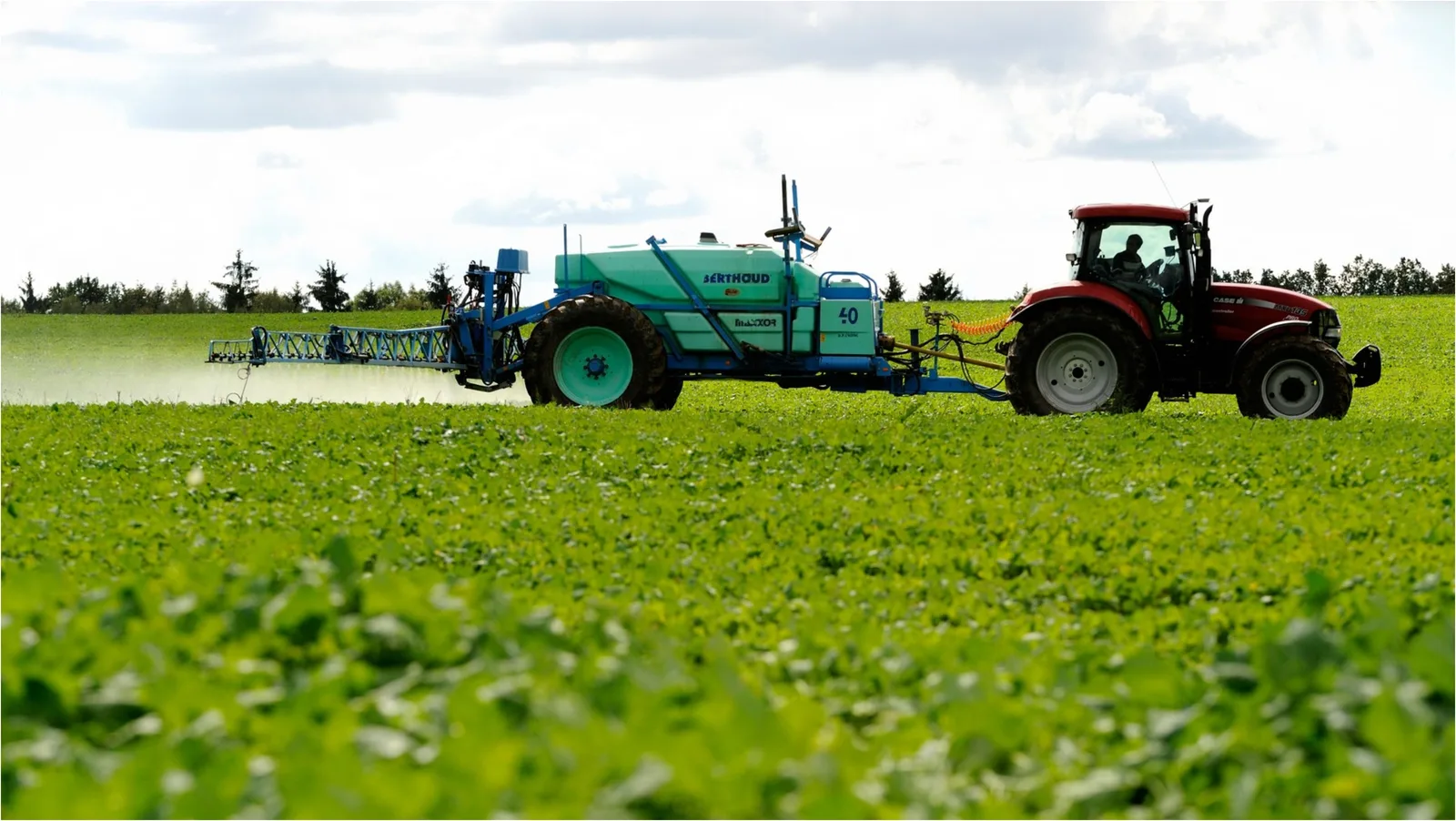 Tractor pe câmp, aplicând îngrășăminte pentru culturile agricole.