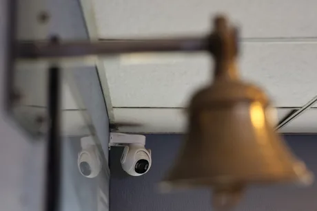 Cameră de supraveghere montată lângă un clopot într-un mediu urban.