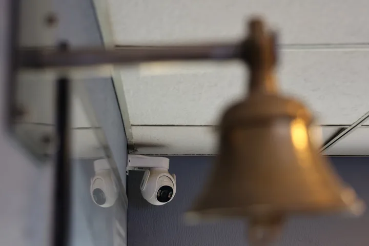 Cameră de supraveghere montată lângă un clopot într-un mediu urban.