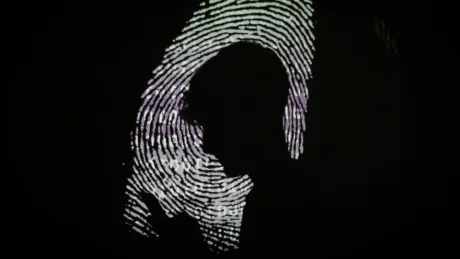 Silhouette umană în fața unui fundal cu amprente digitale.