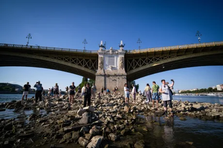 Oameni pe malul Dunării, în fața unui pod, în condiții de secetă extremă.