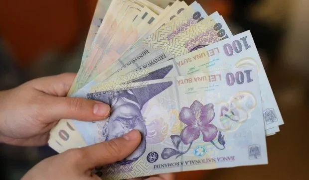 Bancnote românești în mâinile unei persoane, simbolizând ajutoarele financiare.