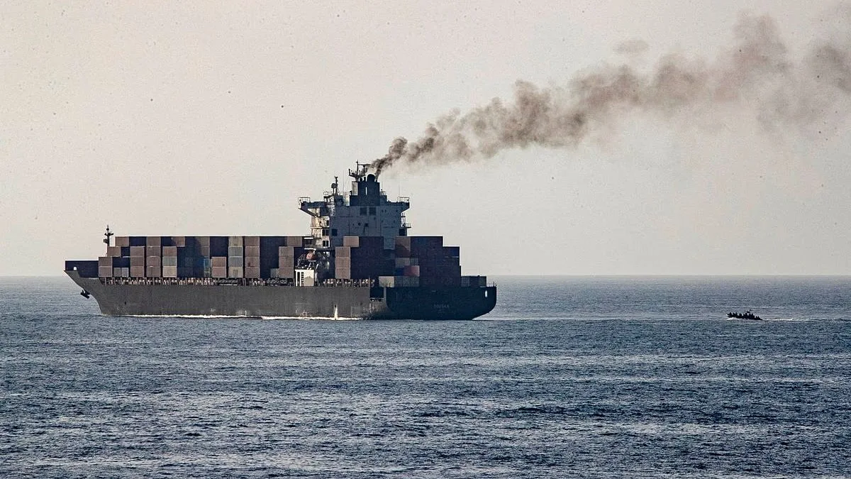 Nava cargo navigând pe mare, emanând fum de la motoare.