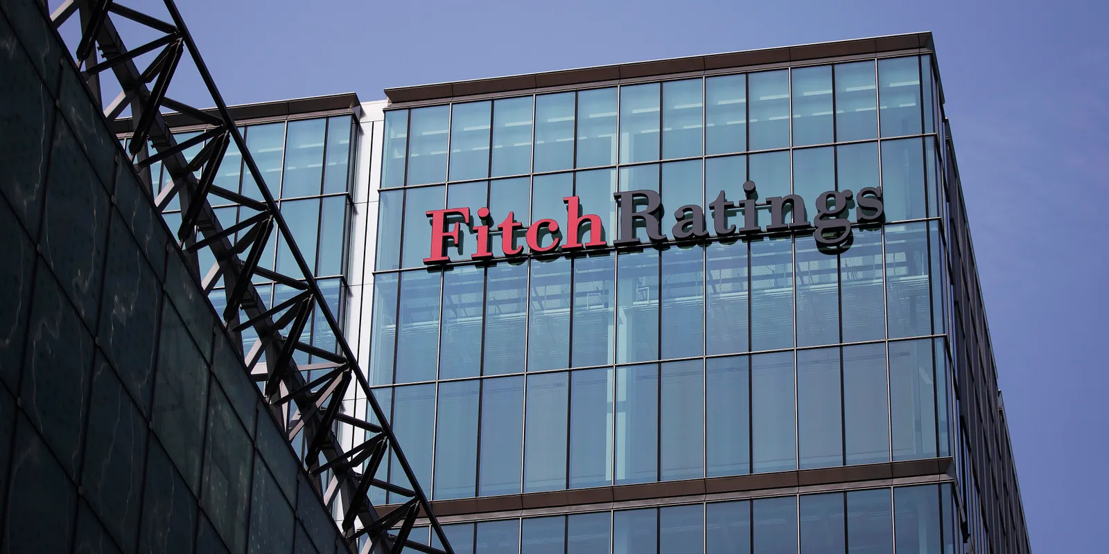 Clădire modernă cu sigla Fitch Ratings pe fațadă, sub un cer senin.