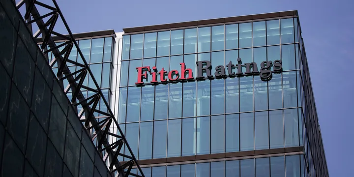 Clădire modernă cu sigla Fitch Ratings pe fațadă, sub un cer senin.