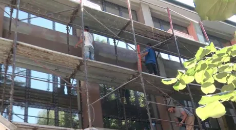 Lucrări de construcție pe un șantier, cu muncitori pe schele.