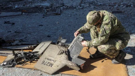Un soldat examinează resturi de echipament militar distrus.