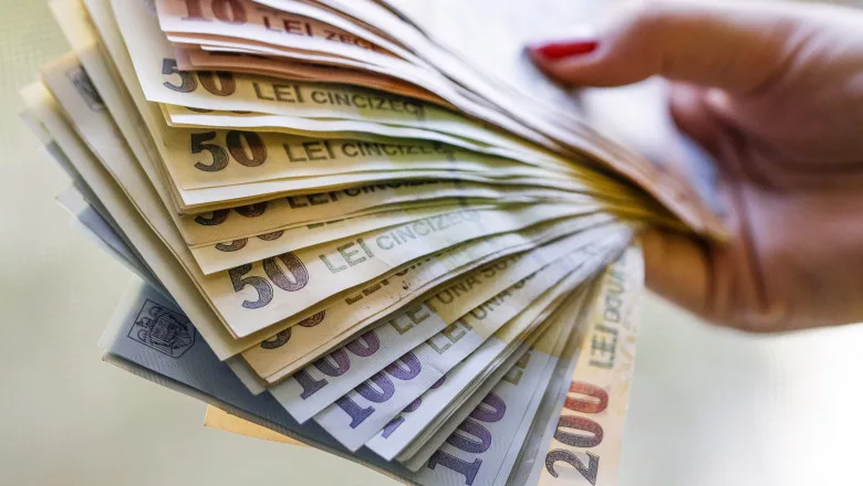 Bancnote românești de diverse valori, simbolizând piața financiară.