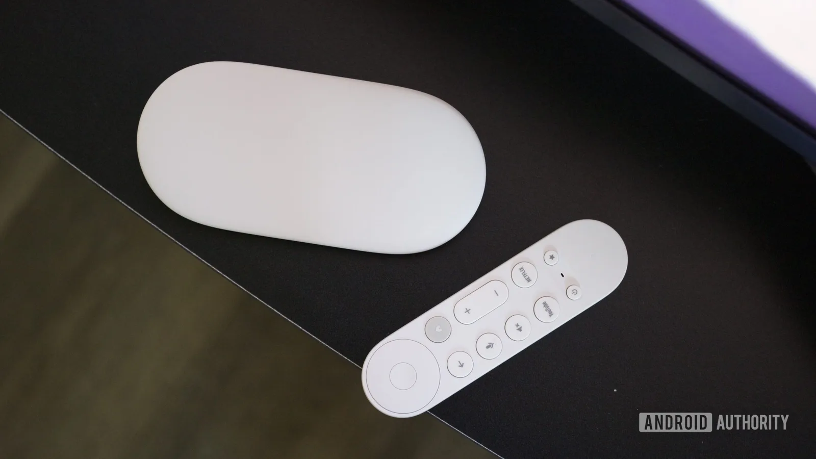Telecomanda Google TV pe un birou, evidențiind designul său minimalist.