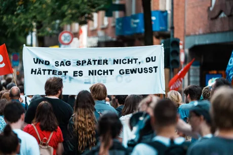 Protest cu oameni care poartă un banner cu mesaj politic în oraș.
