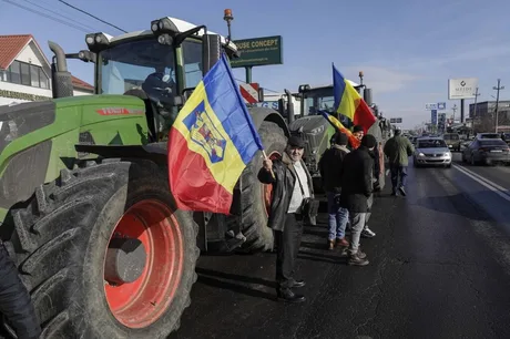 Fermieri protestând cu tractoare și steaguri naționale pe o stradă din București.
