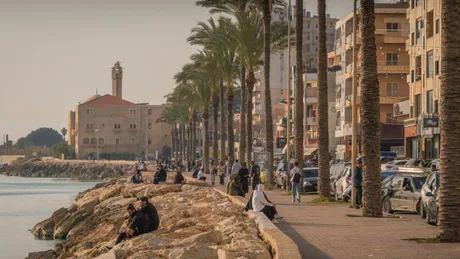 Peisaj urban din Liban, cu palmieri și oameni pe malul apei.
