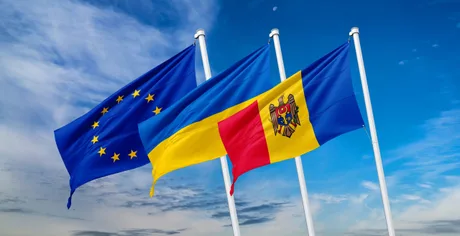 Steagurile Uniunii Europene, Ucrainei și Republicii Moldova fluturând împreună în cerul albastru.