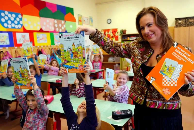 Judit Polgar interacționează cu copii într-o clasă plină de culoare.