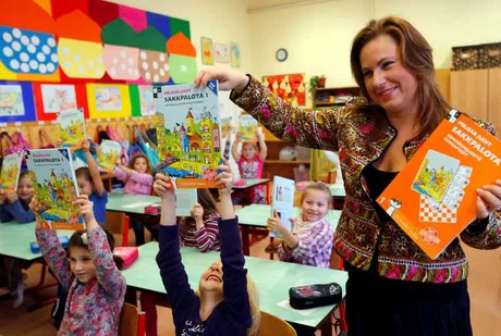 Judit Polgar interacționează cu copii într-o clasă plină de culoare.