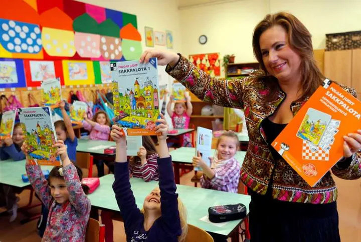 Judit Polgar interacționează cu copii într-o clasă plină de culoare.