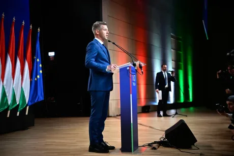Péter Magyar vorbește la un eveniment oficial, cu steaguri în fundal.