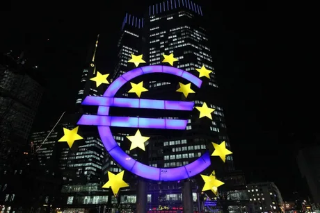Simbolul euro iluminat noaptea, reprezentând Banca Centrală Europeană.