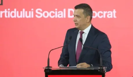 Sorin Grindeanu susține un discurs la PSD, pe fundal roșu.