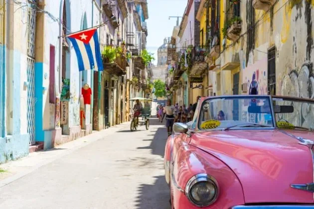 Stradă din Cuba cu clădiri colorate și mașini vechi.