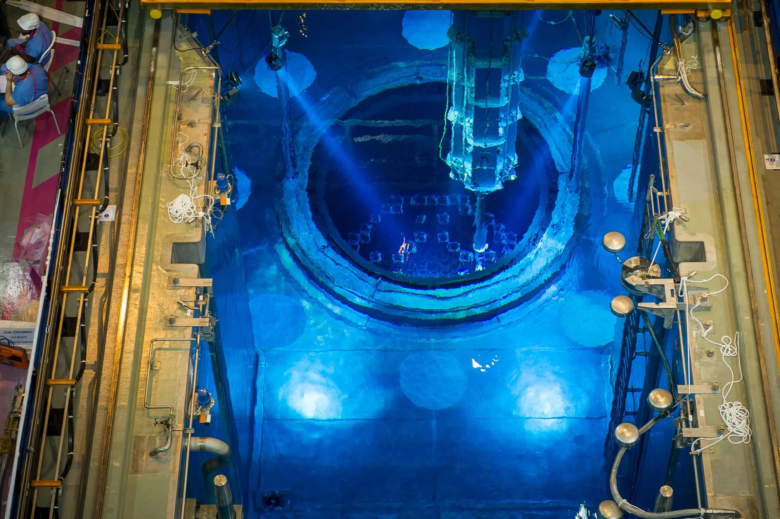 Interiorul unui reactor nuclear, iluminat de lumini albastre, cu echipamente tehnice vizibile.