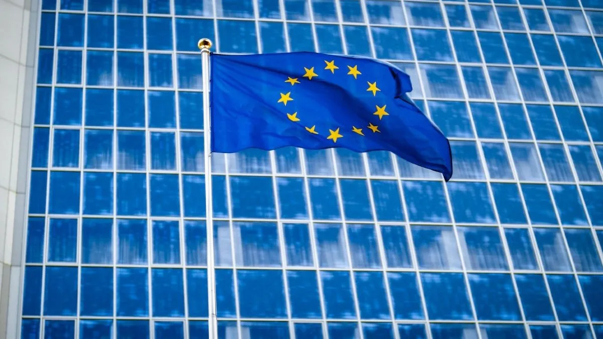 Steagul Uniunii Europene fluturând în fața unei clădiri moderne.