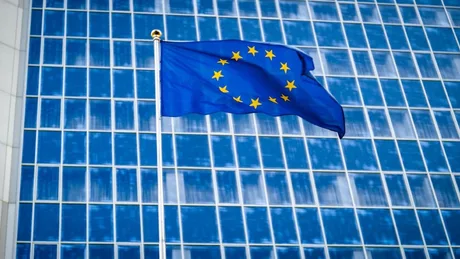 Steagul Uniunii Europene fluturând în fața unei clădiri moderne.