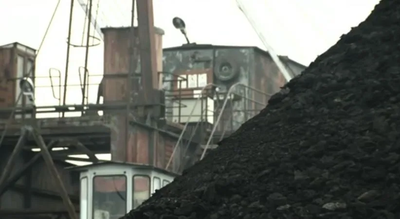 Peisaj industrial cu echipamente miniere și stocuri de cărbune în Valea Jiului.