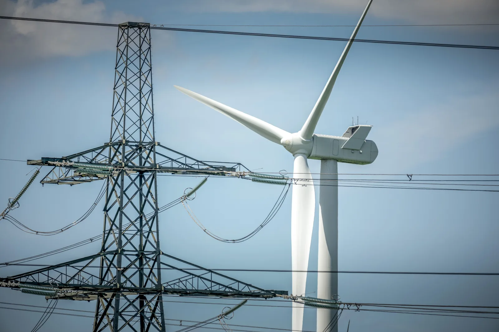 Turbină eoliană și stâlp de electricitate într-un peisaj urban.