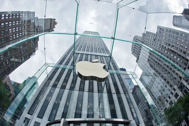 Sediul Apple reflectat în sticlă, cu clădiri în fundal.