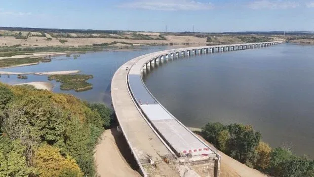 Proiect de infrastructură rutieră peste apă, cu poduri și peisaj natural.