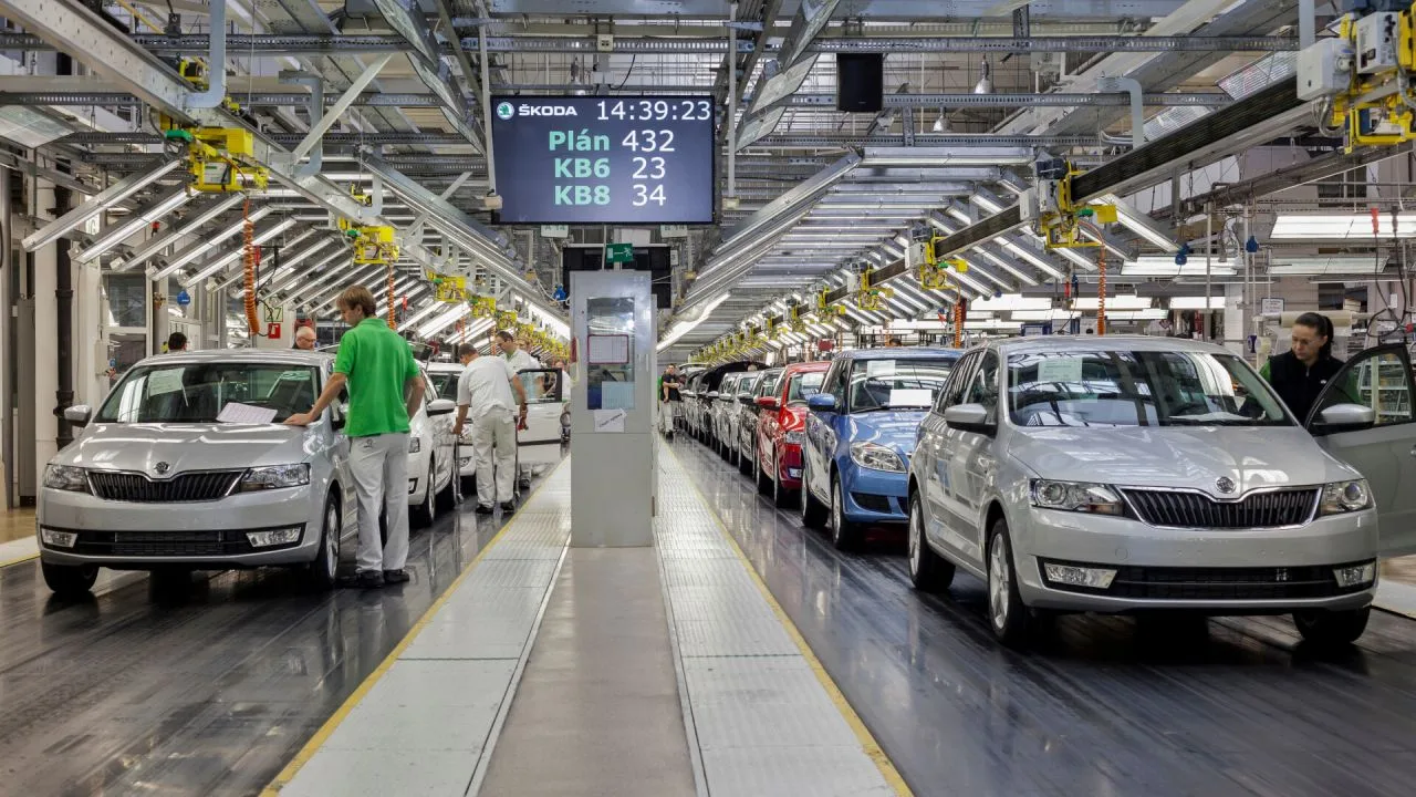 Linie de asamblare auto cu vehicule în producție și muncitori activi.