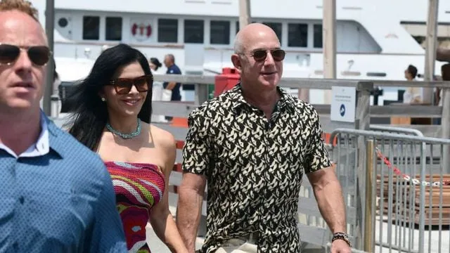 Jeff Bezos și o femeie, plimbându-se pe o promenadă.