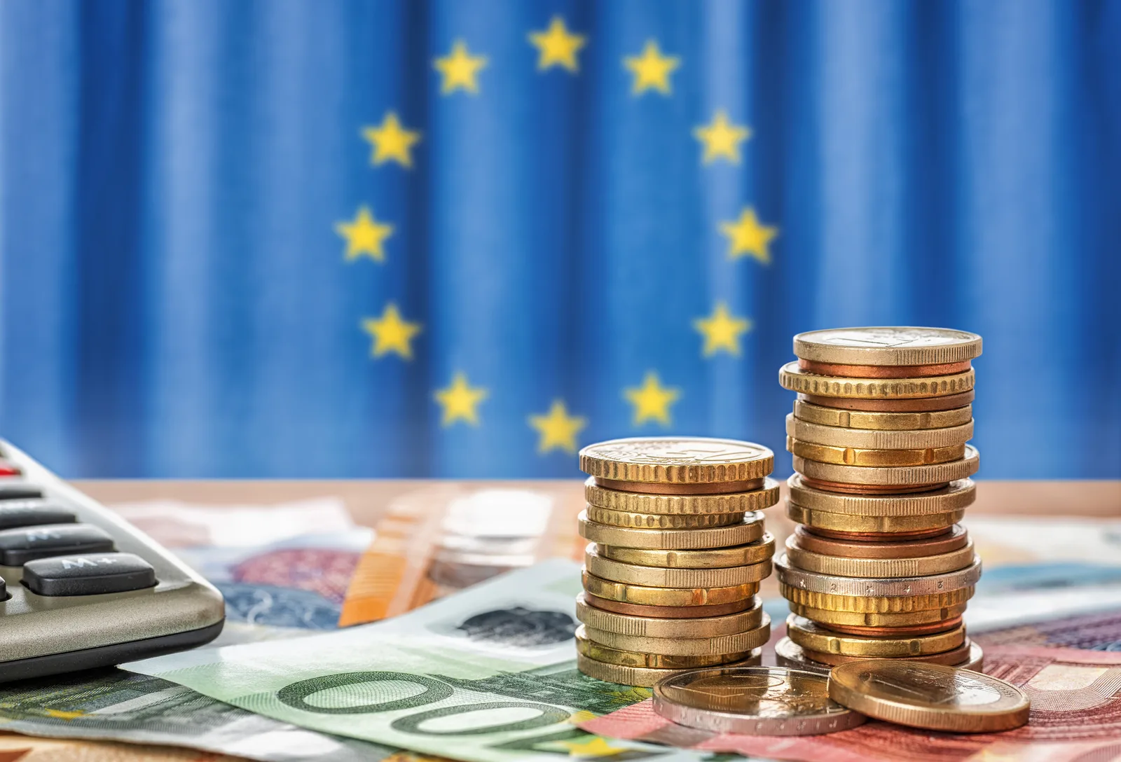 Monede și bancnote pe fundalul steagului Uniunii Europene.
