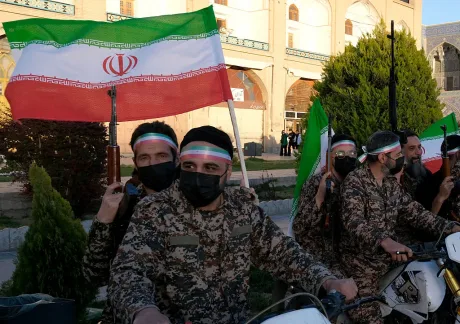 Protestatari iranieni cu steaguri și echipament militar în stradă.