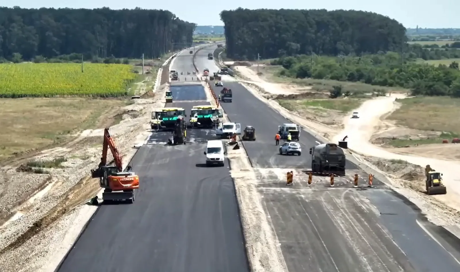 Lucrări de asfaltare pe lotul 1 al autostrăzii A0 Nord, cu utilaje și muncitori activi.