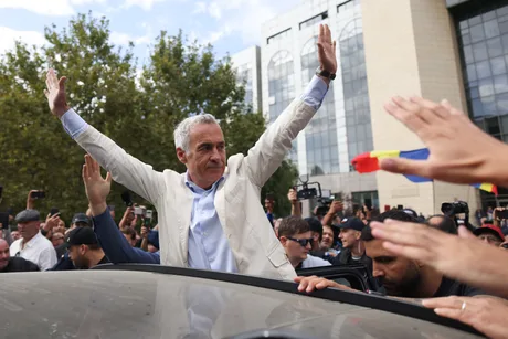 Călin Georgescu salută susținătorii în fața Arestului Central din București.