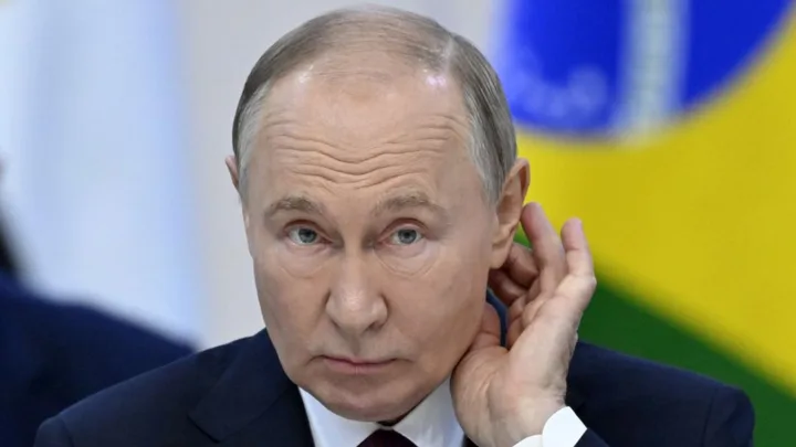 Vladimir Putin ascultând declarațiile oficiale la un summit internațional.