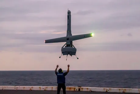 Dronă V-BAT în timpul unui exercițiu pe mare, cu un militar în prim-plan.