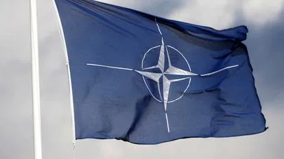 Steagul NATO fluturând în vânt, simbol al alianței europene.