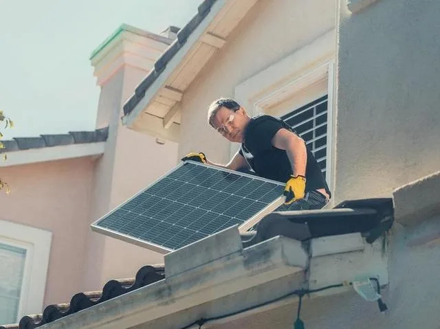 Un prosumator instalează panouri solare pe acoperișul unei clădiri.