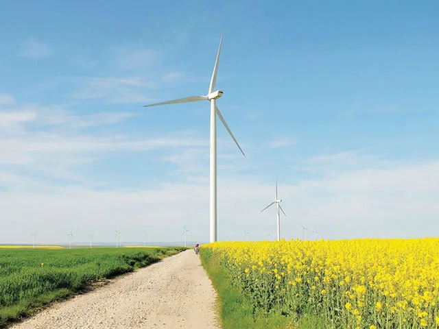 Turbine eoliene într-un peisaj rural din Ungaria, cu câmpuri de floarea-soarelui.
