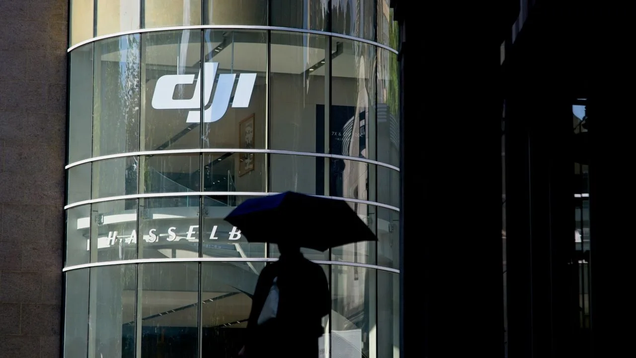 Silueta unei persoane sub un umbreluță, în fața clădirii DJI.