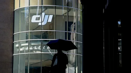Silueta unei persoane sub un umbreluță, în fața clădirii DJI.